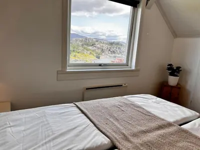 a bed in a bedroom with a large window at Fjord-View Retreat with Free Parking and Fast Internet in Nese