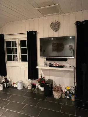 a room with a tiled floor with a large screen television at Hytta for 8 personer skiut/inn in Trysil