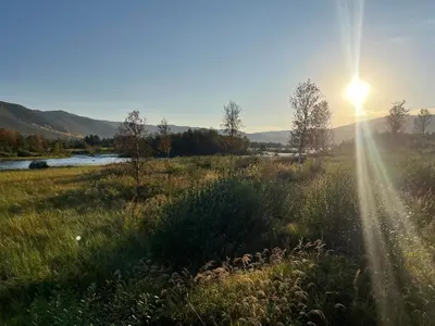 a sun setting over a field with a river at Sentral leilighet på Geilo in Geilo
