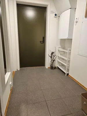 a hallway with a green door and a tile floor at Ny og moderne leilighet, midt i byen1 in Trondheim