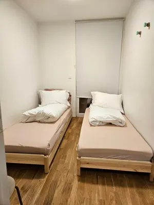 two beds in a room with wooden floors at Ny og moderne leilighet, midt i byen1 in Trondheim