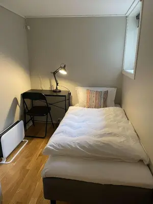 a bedroom with a bed and a desk with a lamp at Apartment close to Aalesund center in Ålesund