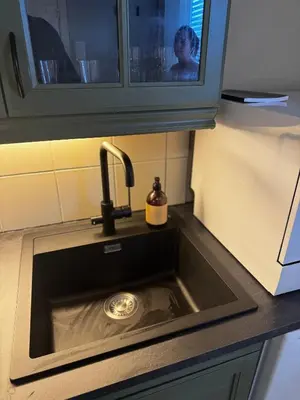 a kitchen sink with a person in the background at Apartment close to Aalesund center in Ålesund
