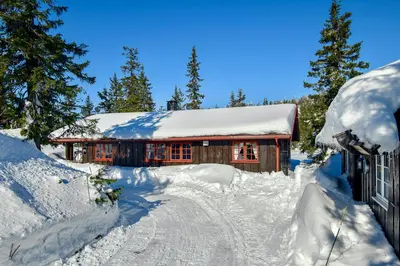 a log cabin covered in snow with a driveway at Family-friendly cabin at Sjusjøen with ski trails, sauna and fireplace in Ringsaker