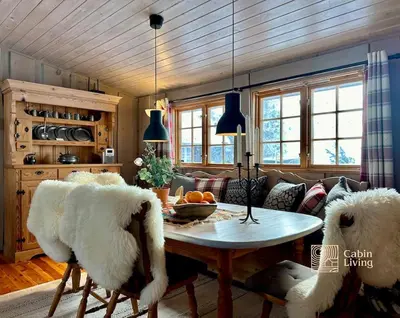 a living room with a table and two white chairs at Family-friendly cabin at Sjusjøen with ski trails, sauna and fireplace in Ringsaker
