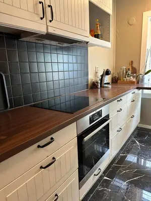a kitchen with white cabinets and a wooden counter top at Leilighet med nydelig utsikt over Bergen in Bergen