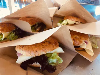 four sandwiches in paper bags on a table at Bed and Brunsj, Sand in Sand