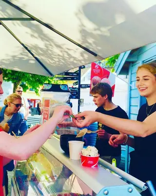 a group of people preparing food at a food stand at Bed and Brunsj, Sand in Sand