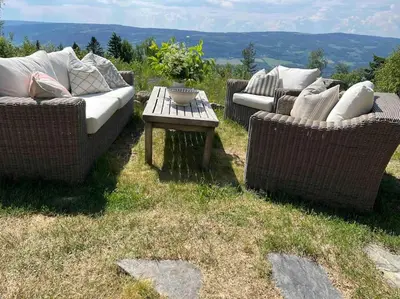 three wicker couches and a table in the grass at Koselig hytte 10 minutter fra Lillehammer sentrum in Lillehammer