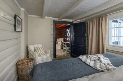 a bedroom with a bed and a chair and a window at Koselig hytte 10 minutter fra Lillehammer sentrum in Lillehammer