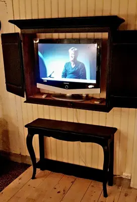 a tv sitting on a wall with a table at Kvammehuset på Gamle Lærdalsøyri in Lærdalsøyri