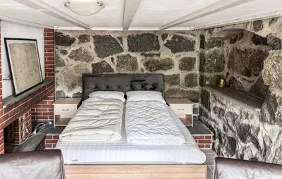 a bed in a room with a stone wall at 4 Bedroom Awesome Home In Nedre Vats in Stokka
