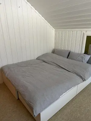 a bed in a room with white walls at Stort hus sentralt i Lillehammer in Lillehammer
