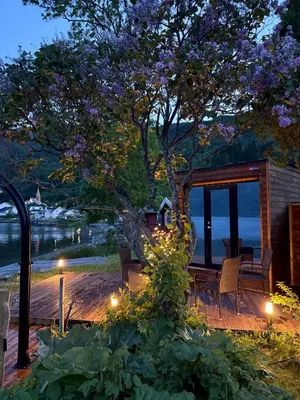 a wooden deck with a tree and some lights at Dalsøren Camping og hytter in Luster