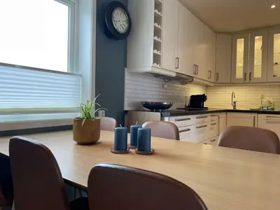 a kitchen with a wooden table with chairs and a clock at Moderne rekkehus, god standard. in Ålesund