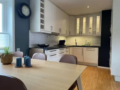 a kitchen with a table and a clock on the wall at Moderne rekkehus, god standard. in Ålesund