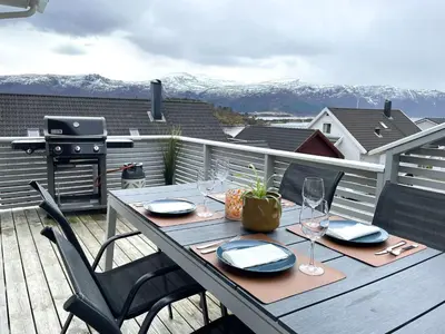 a wooden table with glasses and plates on a balcony at Moderne rekkehus, god standard. in Ålesund