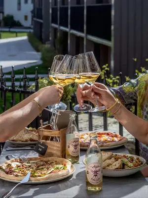 two people holding glasses of wine at a table with pizzas at Vertshuset Konow in Bergen