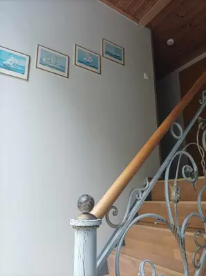 a staircase with a metal railing with pictures on the wall at Sveciu namai in Vikedal
