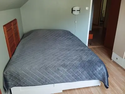 a bed in a small room with a gray bedspread at Sveciu namai in Vikedal