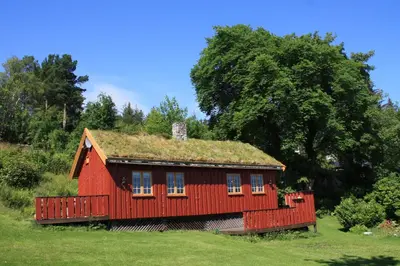 a red house with a grass roof on a field at Åkviktunet hytte nord in Averoy