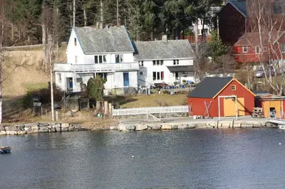 a large white house and a red house next to the water at Åkviktunet hytte nord in Averoy