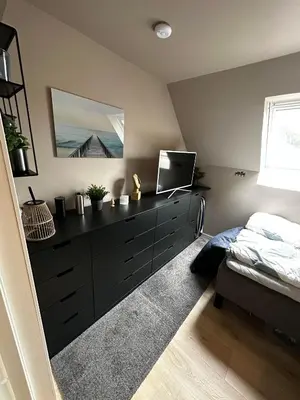 a bedroom with a black dresser and a bed at Modern Penthouse in Sandviken in Bergen