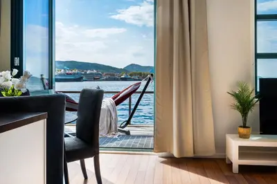 a living room with a view of a boat at New! Sea front apt. with terrace above the sea! in Bergen