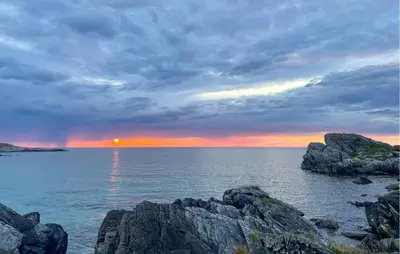 a sunset over a large body of water with rocks at 2 Bedroom Lovely Home In Raudeberg in Raudeberg