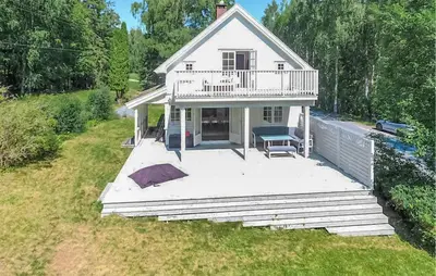 a white house with a balcony on a yard at Awesome Home In Noresund With Wifi in Noresund