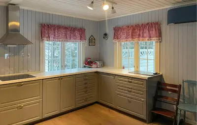 a kitchen with white cabinets and a sink and two windows at Awesome Home In Noresund With Wifi in Noresund