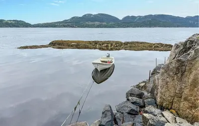 a boat sitting on the water next to some rocks at Amazing Home In Vikebygd With Wifi in Vikebygd