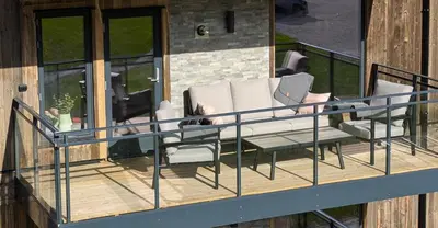 a balcony with a couch and chairs on a house at Ski in/out Appartment Hemsedal in Hemsedal