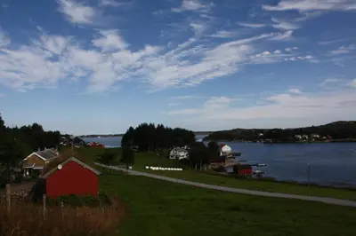 a red house on a hill next to a body of water at Åkviktunet hytte Sør in Averoy