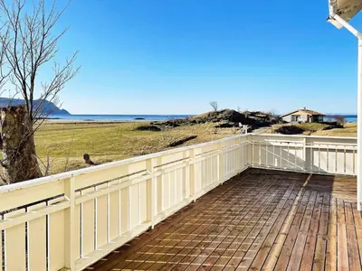 a wooden deck with a white fence and the ocean at 8 person holiday home in Bremanger in Grotle