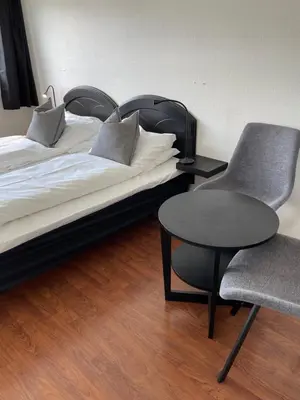 a bedroom with two beds and a chair and a table at Oppdalsporten Motell in Oppdal