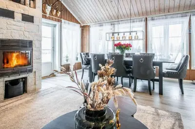 a living room with a table and a fireplace at A wonderful estate of two houses for all seasons! in Trysil