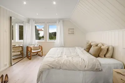 a white bedroom with a large bed and a window at A beautiful 3-bedroom apartment with stunning views and free parking in Bergen