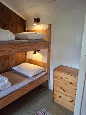 a bedroom with two bunk beds and a wooden cabinet at Bjørgebu Camping AS in Mysusæter