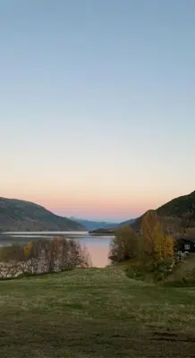 a view of a lake with trees and a grass field at New appartment in Lom inkl bedding in Lom