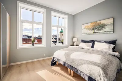 a bedroom with a bed and two windows at Allmenningen Apartments in Bergen