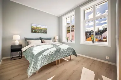 a bedroom with a bed and two windows at Allmenningen Apartments in Bergen