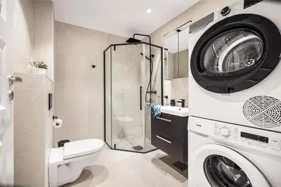 a bathroom with a washing machine and a shower at Allmenningen Apartments in Bergen