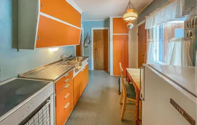 a kitchen with orange cabinets and a sink and a table at Gorgeous Home In Os I Østerdalen in Os