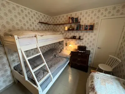 a bedroom with a bunk bed with a ladder and a desk at Skogly - det gode livet på landet in Stryn