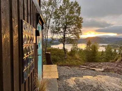 a door of a house with the sunset in the background at Stabbur med fantastisk utsikt! in Steinkjer