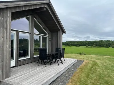 a wooden deck with a table and chairs on it at Moderne feriehus i Bud in Bud