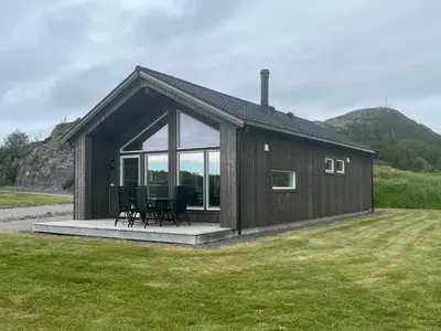 a small cabin with a table and chairs in a yard at Moderne feriehus i Bud in Bud