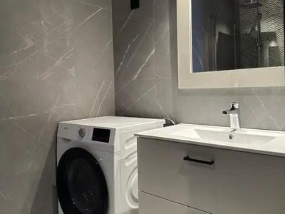 a bathroom with a washing machine and a sink at Riddergaardens panorama in Beitostøl