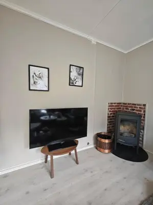 a living room with a fireplace and a flat screen tv at Rekkehus Tyssedal Trolltunga in Tveit
